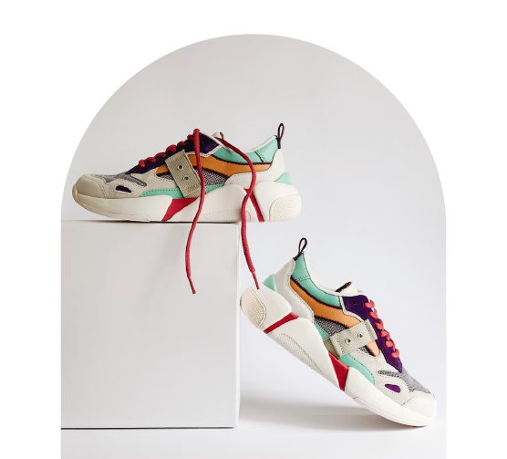 F&auml;rgglada sneakers med r&ouml;da skosn&ouml;ren, placerade p&aring; och bredvid en vit piedestal